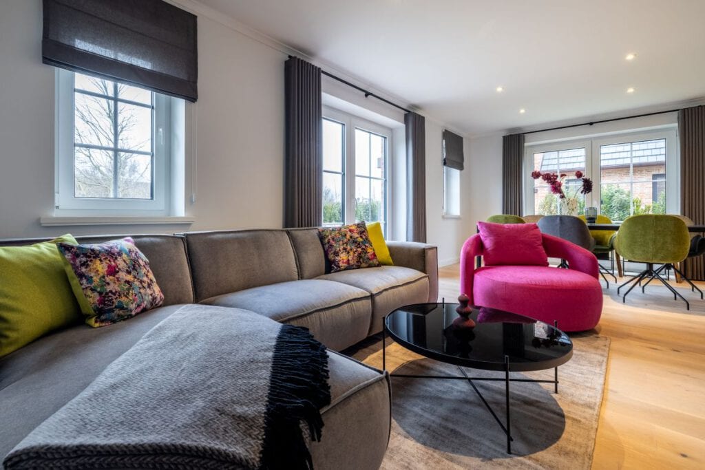 Landhaus Stricker – Wohnbereich mit Sofa und farbigen Akzenten, Boutiquehotel Sylt