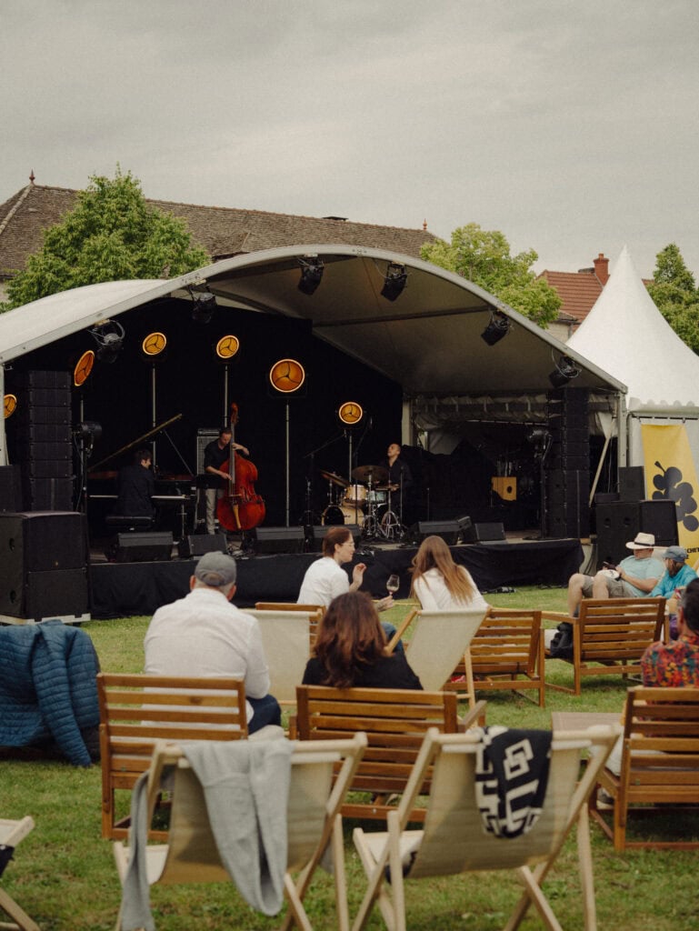 Jazzkonzert im Freien mit Trio auf Bühne und Publikum auf Liegestühlen, Destinationsevent