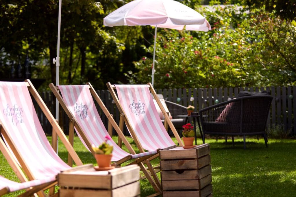 Erika's Garden Club – rosa-weiß gestreifte Liegestühle im sommerlichen Hotelgarten