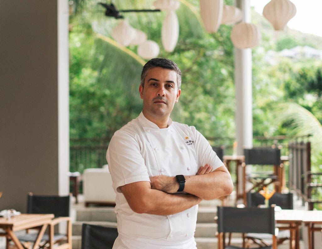 Küchenchef im weißen Kochgewand in tropischem Hotelrestaurant, Luxushotellerie Gastronomie