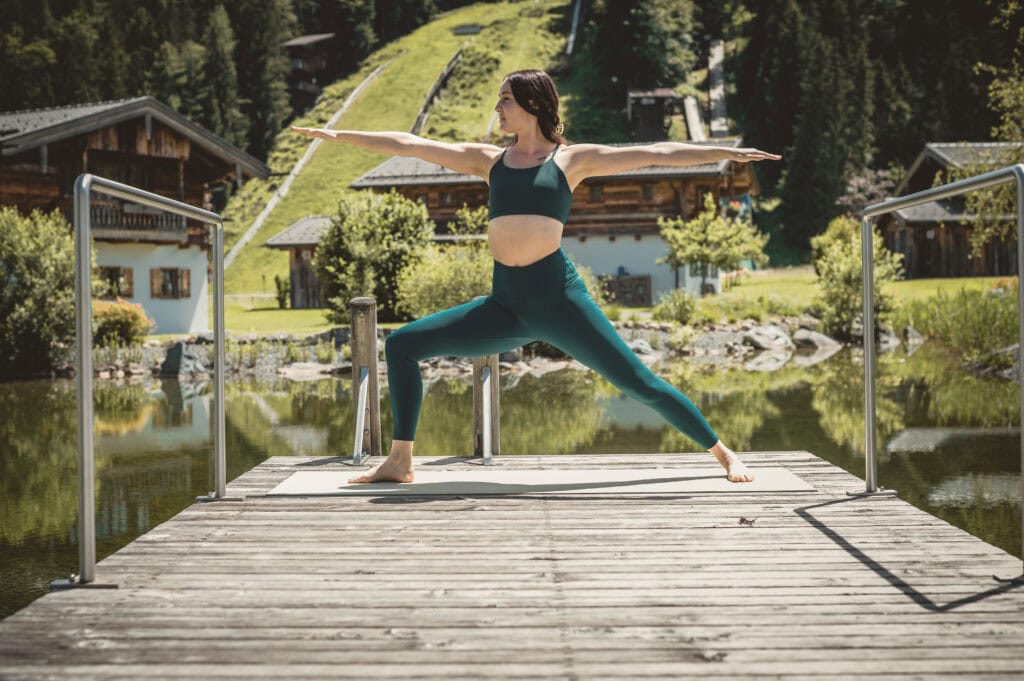 Yoga auf dem Steg am Natursee mit Bergpanorama, Wellness Retreat Österreich