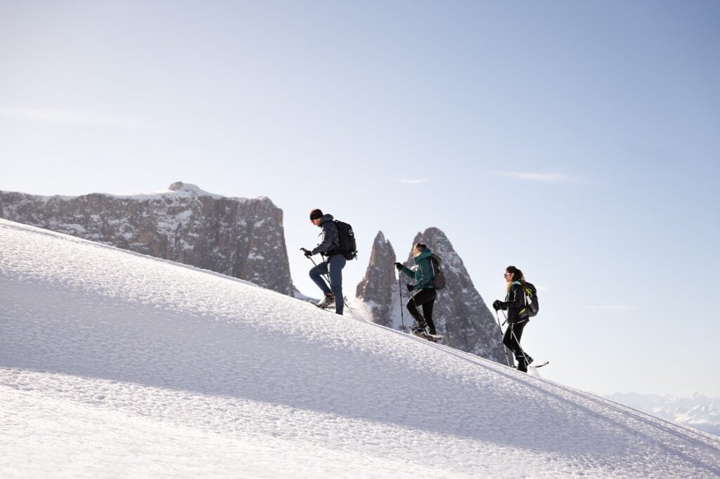 Drei Wanderer auf verschneitem Bergpfad, Winterlandschaft, klare Himmel, segara Kommunikation – PR‑&.