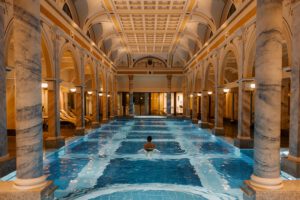 Innenansicht eines luxuriösen Spa-Pools mit Säulen und kunstvoller Decke, entspannte Atmosphäre.